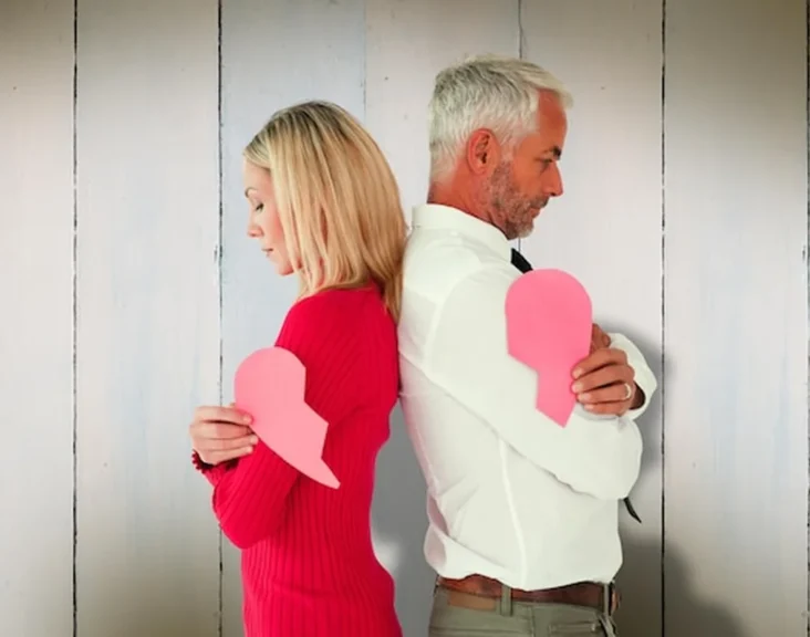 Para trzymająca dwie połówki złamanego serca na drewnianych deskach